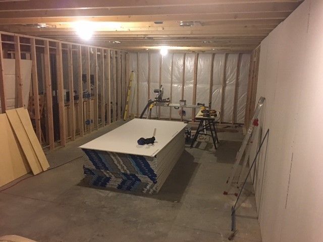 A room under construction with a large piece of drywall on the floor.