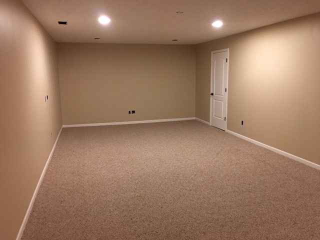 An empty room with a carpeted floor and tan walls