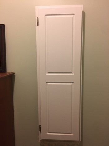 A white door is hanging on a wall in a room next to a dresser.