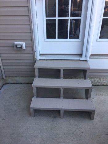 A set of stairs leading up to a door on the side of a house.