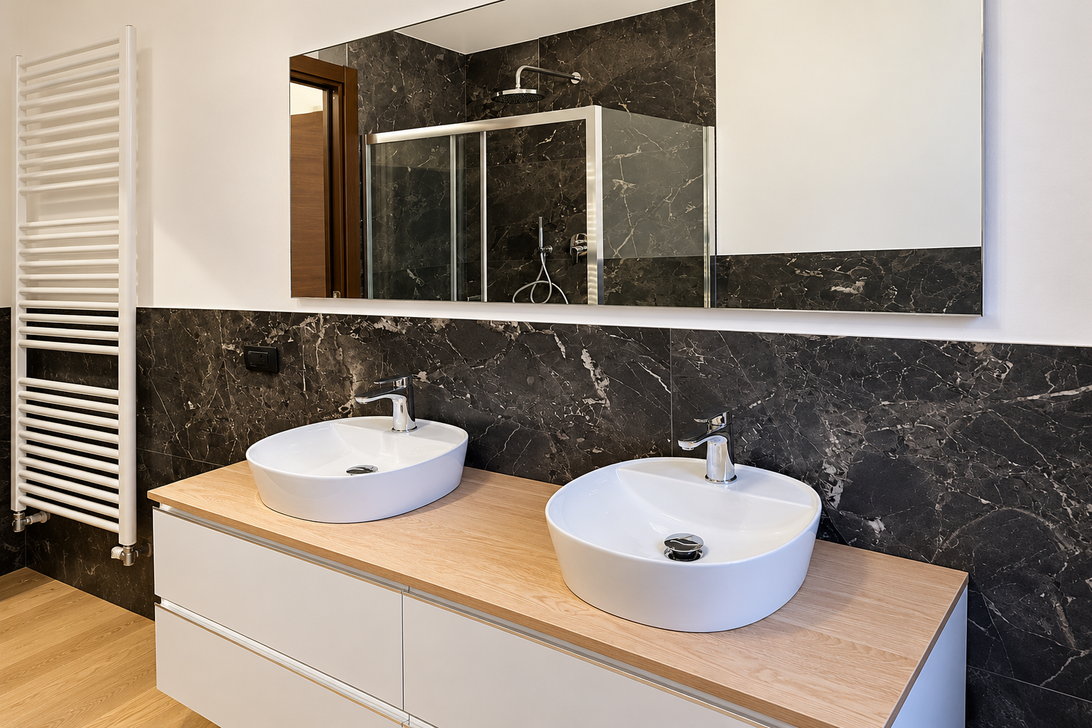 Mobile bagno moderno con due lavabi da appoggio bianchi, piano in legno e grande specchio su una parete rivestita con piastrelle in marmo scuro