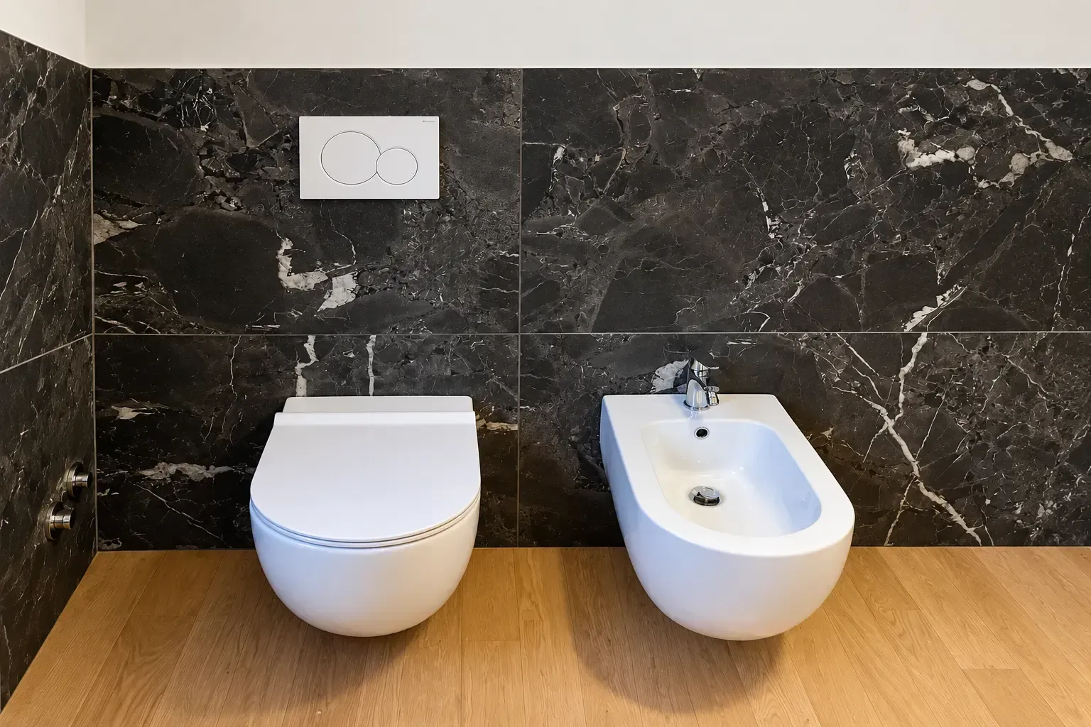 Bagno moderno con WC sospeso e bidet bianco, parete in marmo scuro e pavimento in legno