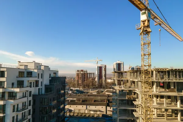 Cantiere edile con gru a torre e palazzi residenziali in costruzione sotto un cielo azzurro e limpido