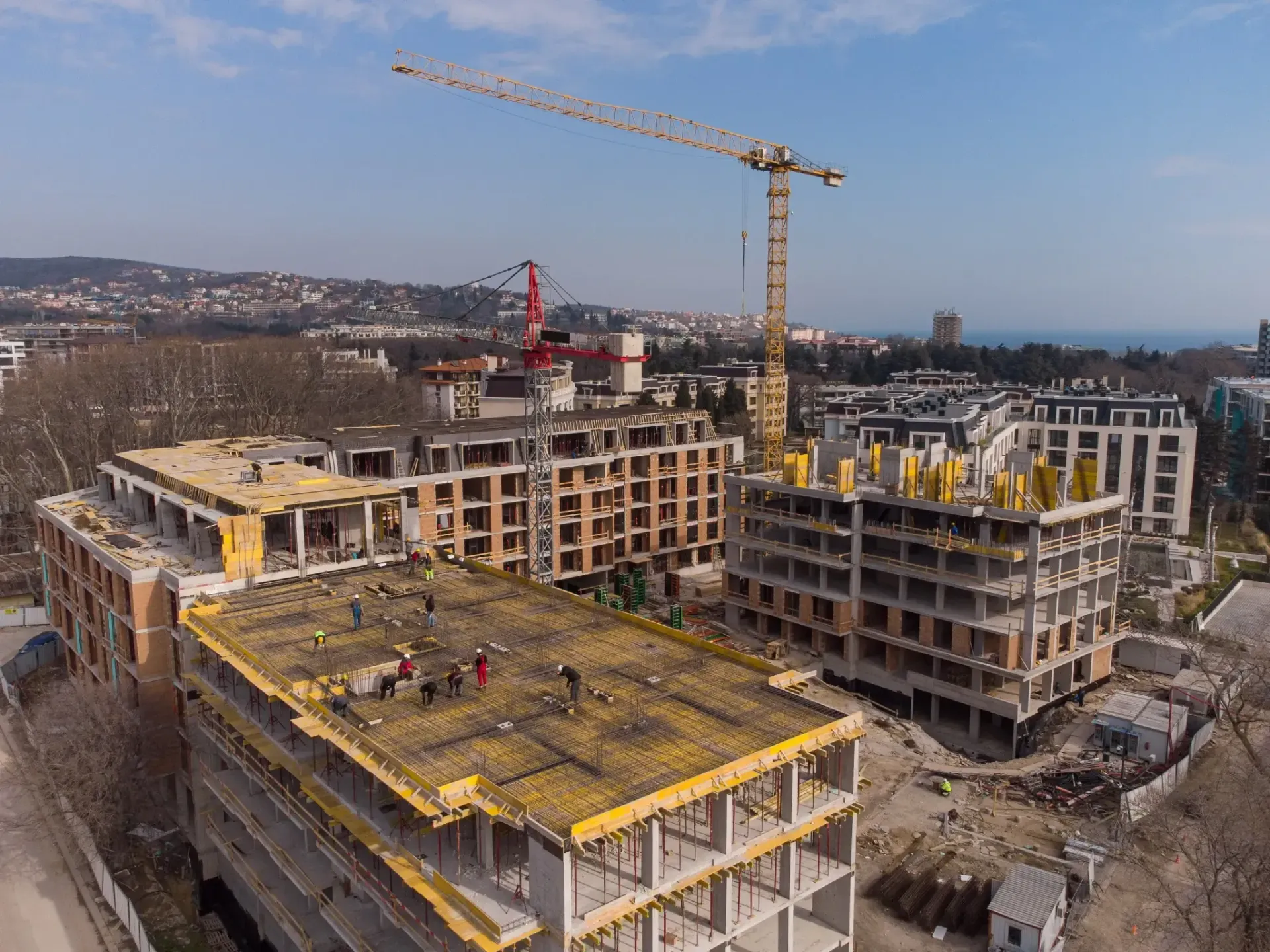 Cantiere edile con diversi edifici incompiuti e una gru alta sotto un cielo sereno