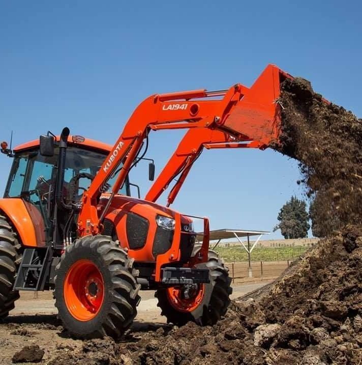 Orange Tractor Loader Dumping Soil at a Construction Site Under a Clear Blue Sky — Casali's in Mareeba, QLD