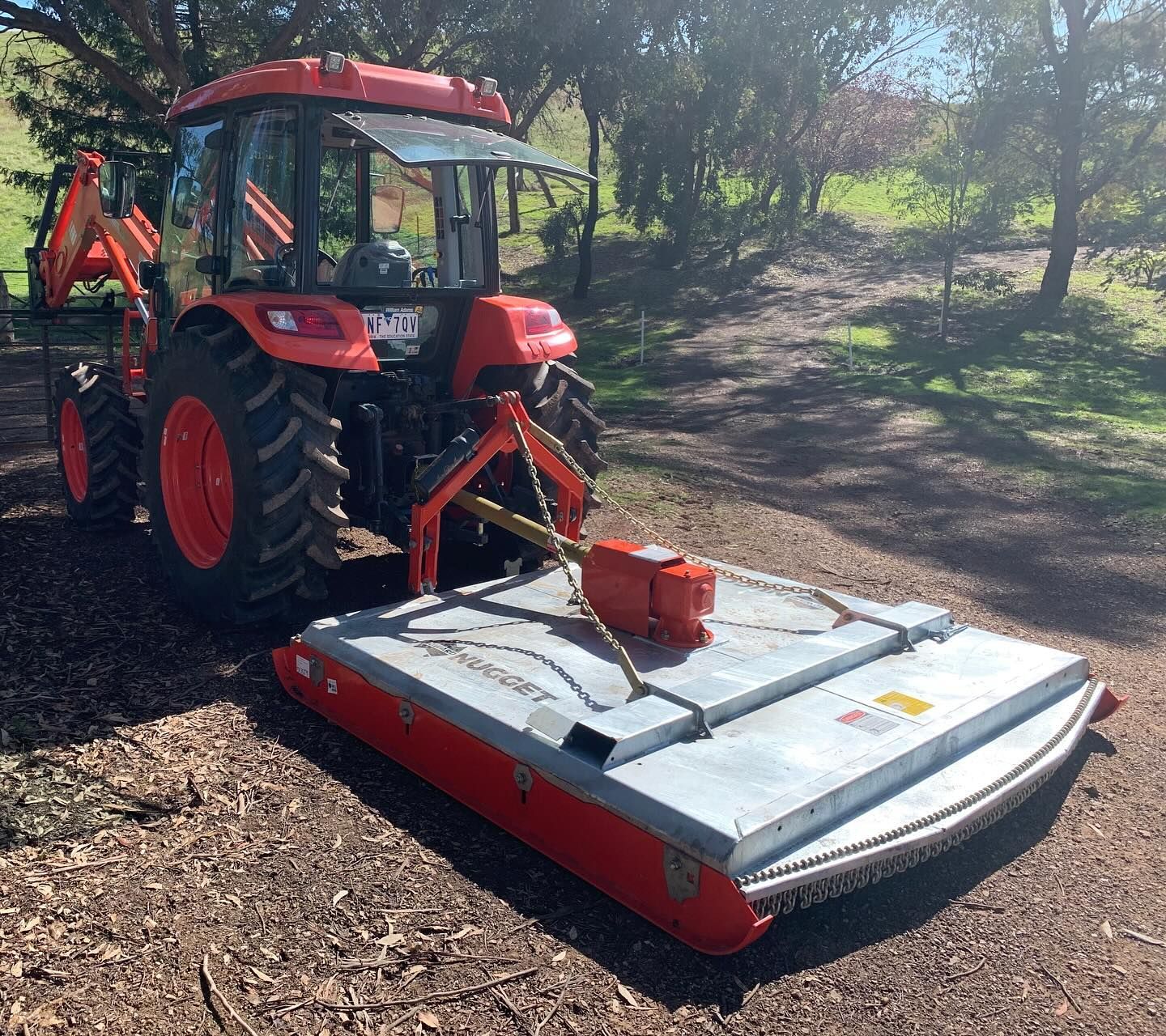 Red Tractor With a Front Mower Attachment Parked on a Dirt Path in a Sunny Wooded Area — Casali's in Mareeba, QLD