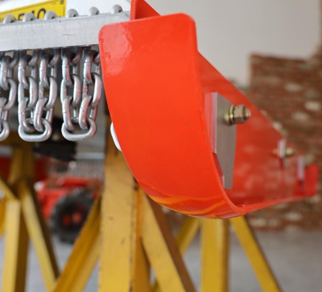 Red Industrial Machine Guard With Metal Hooks in a Workshop, Close-up on Yellow Support Stands — Casali's in Mareeba, QLD