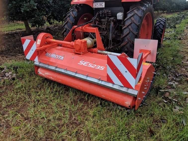 Red Tractor-mounted Rotary Mower With Red-and-white Hazard Stripes in a Muddy Field — Casali's in Mareeba, QLD