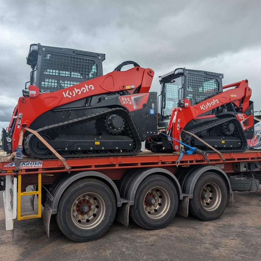 Two Red Kubota Construction Machines Strapped on a Flatbed Trailer Under a Cloudy Sky — Casali's in Mareeba, QLD