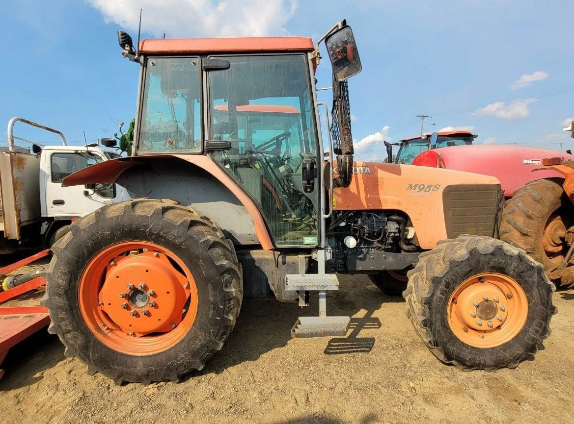 Orange Tractor Parked on a Dirt Lot With a Red Farm Implement Attached on the Left — Casali's in Mareeba, QLD