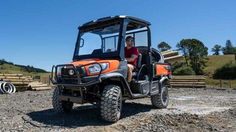 Orange and black off-road utility vehicle parked on gravel, with a person seated inside under a blue sky. — Casali's in Mareeba, QLD