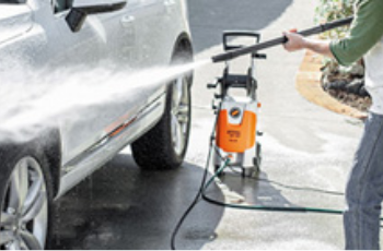 Person Pressure-washing a Silver Car Outdoors With an Orange Washer and Strong Water Spray — Casali's in Mareeba, QLD