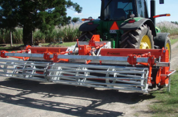Red Hay Rake Attachment on a Tractor in a Sunny Farm Field — Casali's in Mareeba, QLD