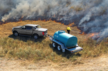 Pickup Truck Towing Blue Water Tank Near a Grass Fire With Smoke and Flames in the Background — Casali's in Mareeba, QLD