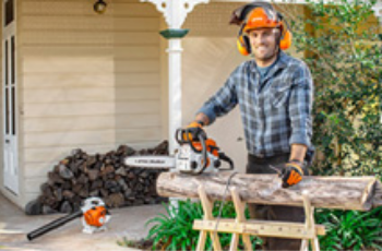 MAN Wearing Safety Gear Using a Chainsaw on a Log in a Backyard Workspace — Casali's in Mareeba, QLD