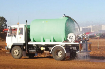 Green Tanker Truck Spraying Water on a Dirt Field Outdoors — Casali's in Mareeba, QLD