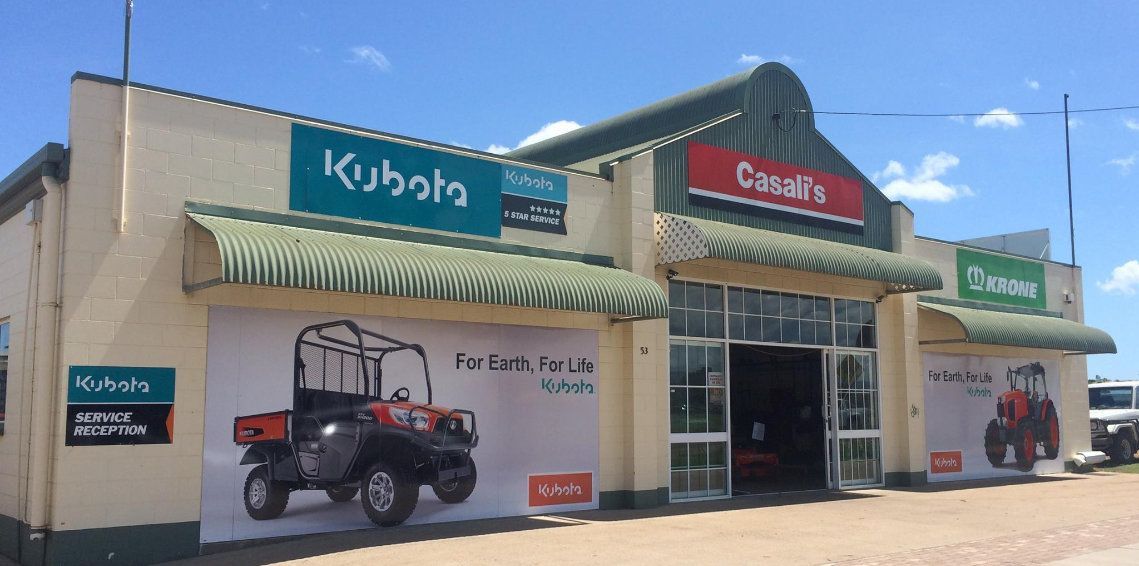 Kubota and Case IH dealership storefront with tractor mural and parked utility vehicles