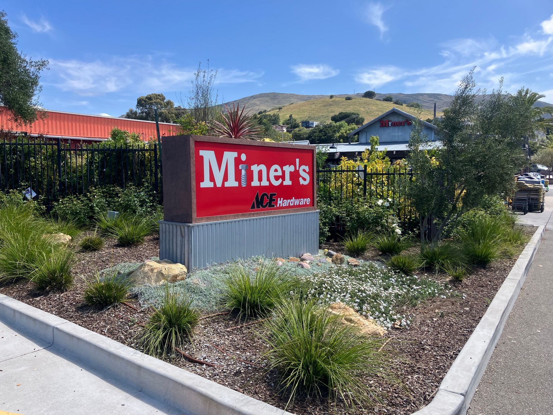 Miner’s Ale House sign in a landscaped roadside garden with hills in the background