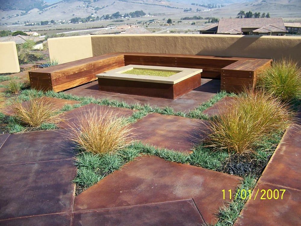 Outdoor patio with built-in seating, a fire pit, and desert landscaping overlooking hills.