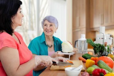 Caregiver cooking with elderly woman