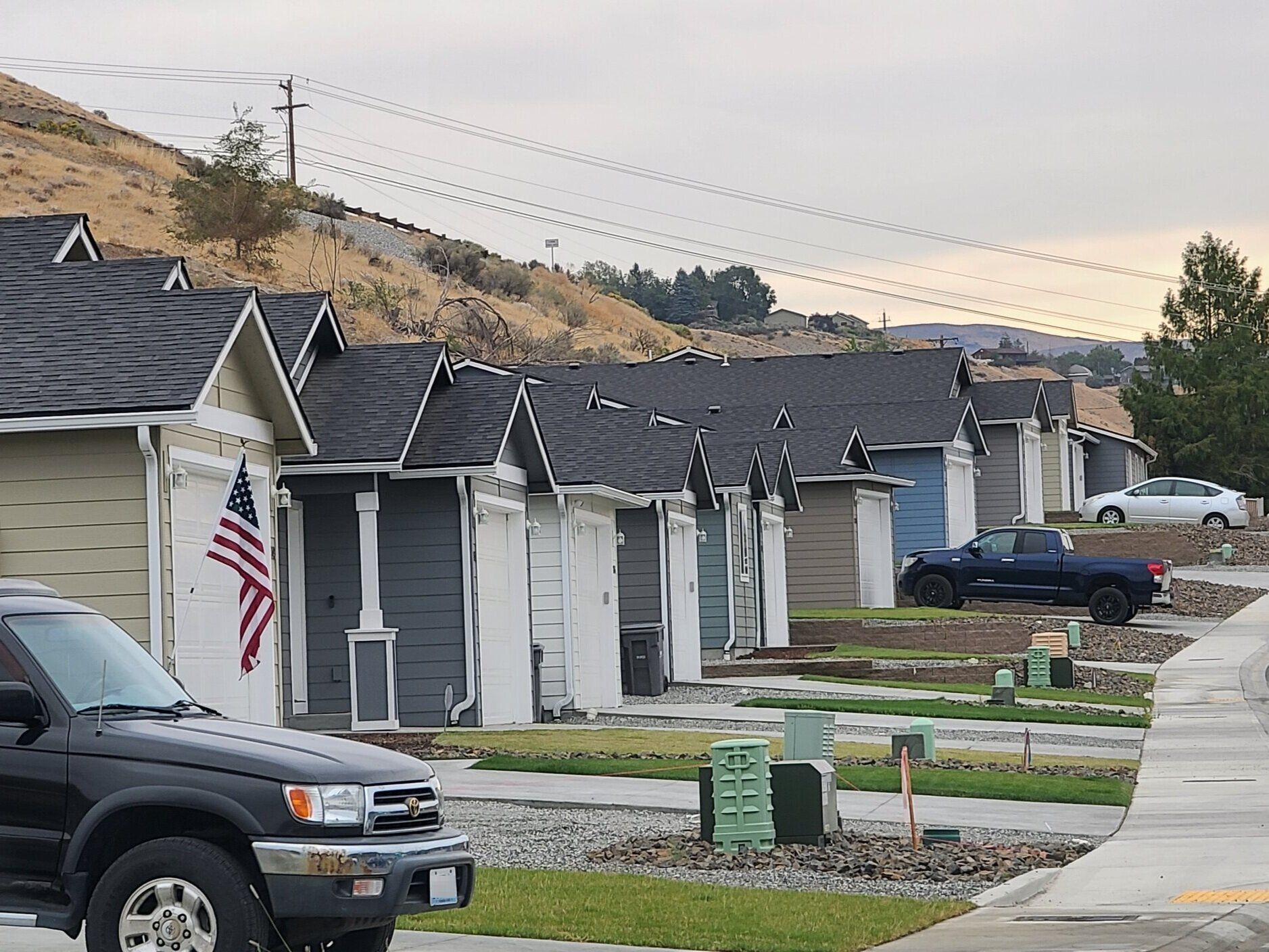 A black truck is parked in front of a row of houses.