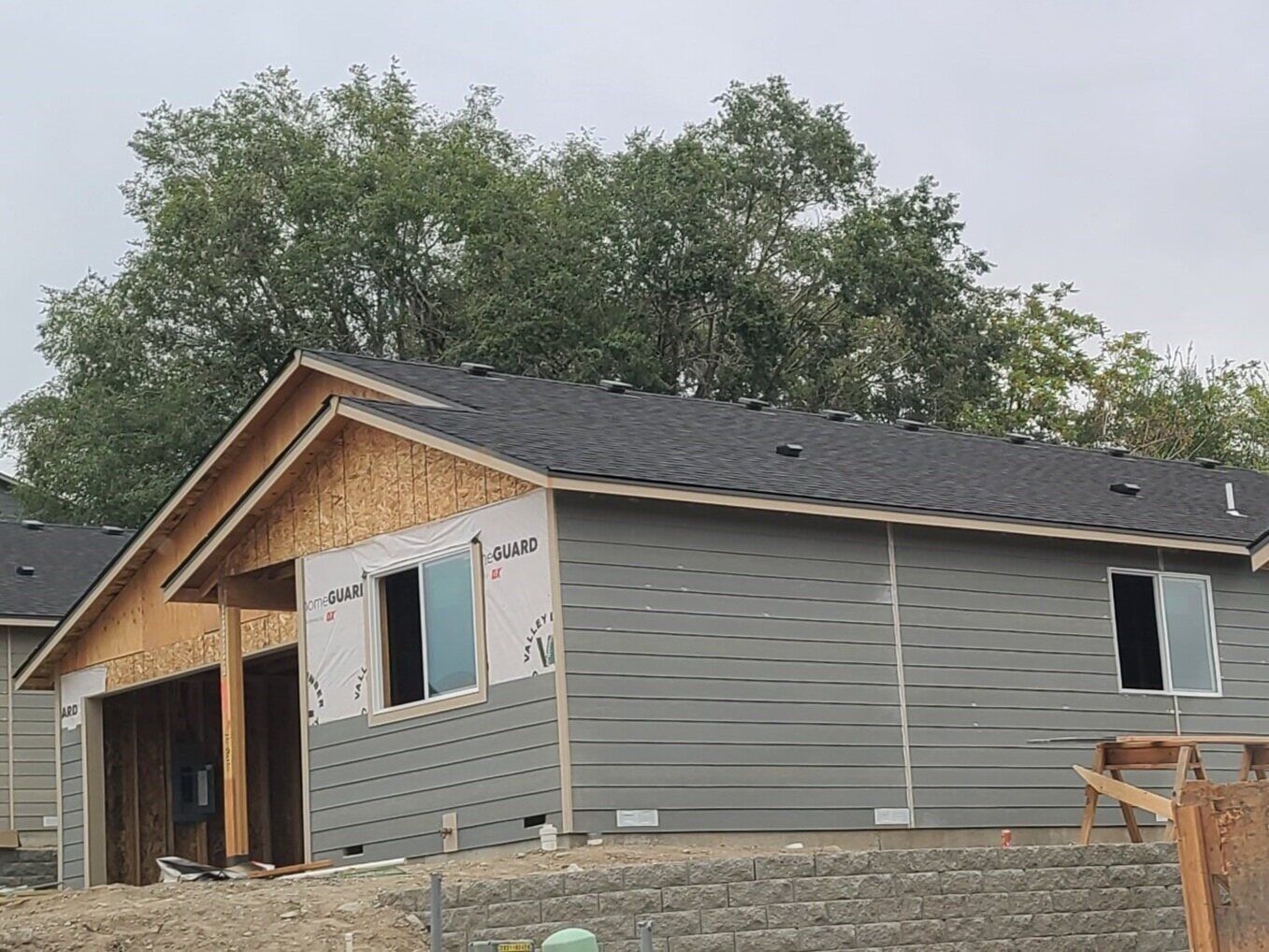 A house is being built on a hill with trees in the background.