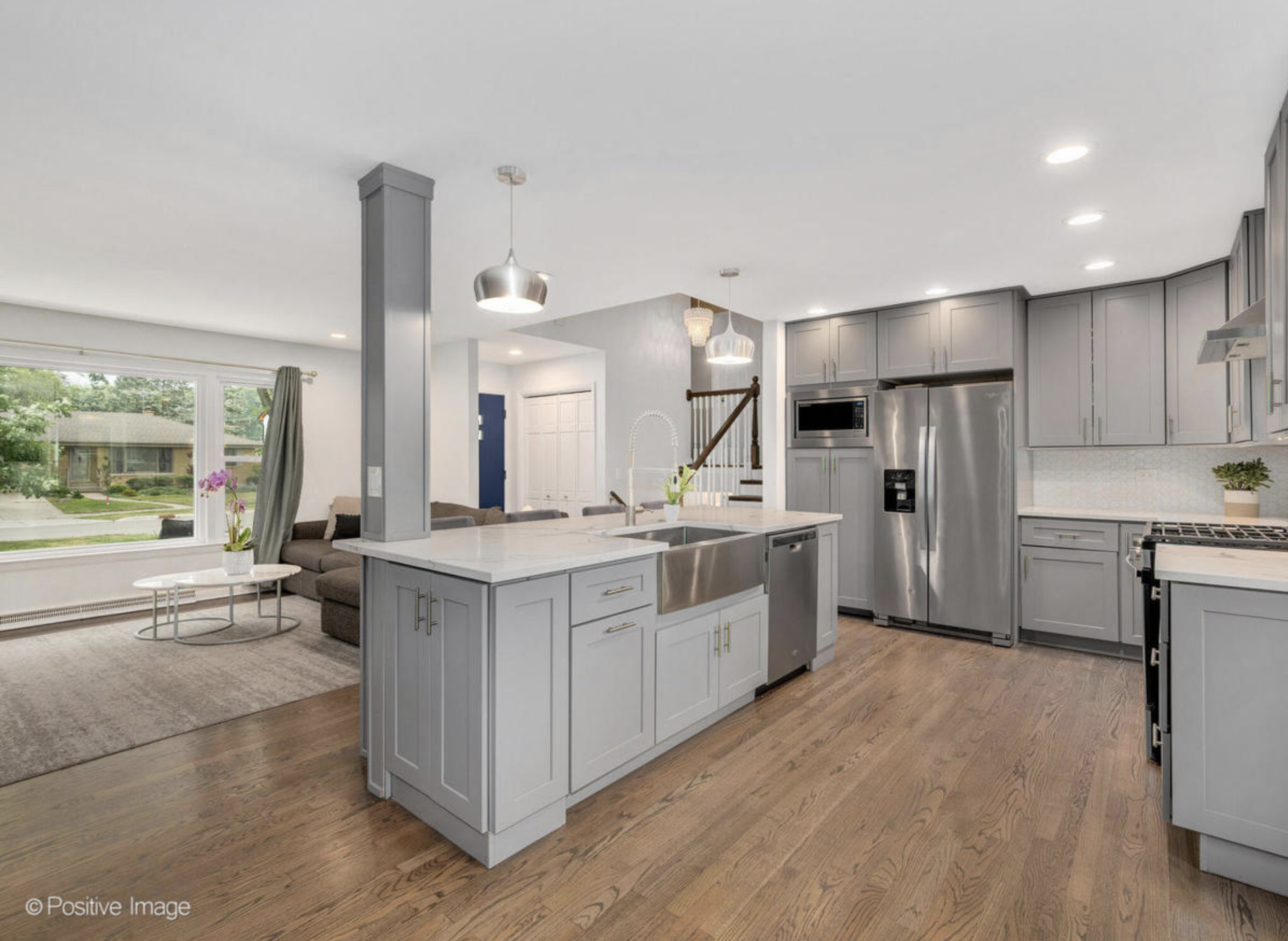 A kitchen with white cabinets and stainless steel appliances and a large island in the middle.