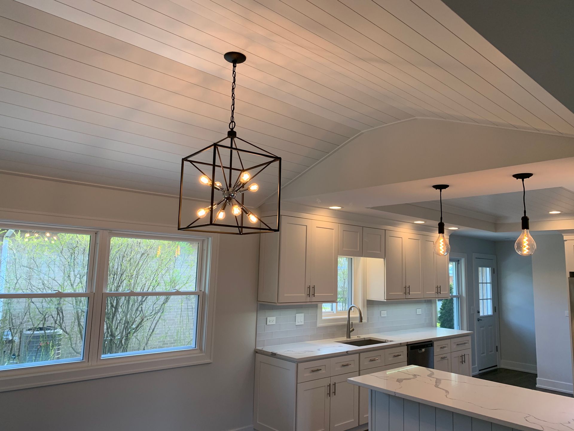 A kitchen with white cabinets and a chandelier hanging from the ceiling.