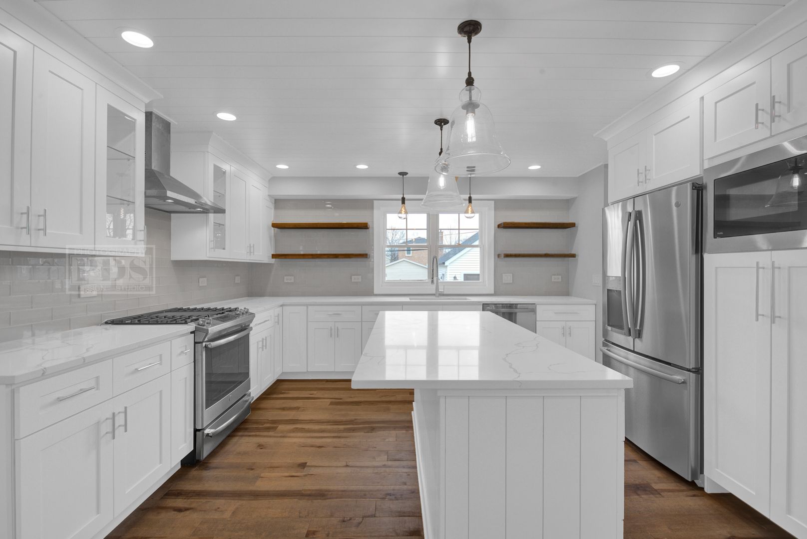 A kitchen with white cabinets , stainless steel appliances , and a large island.