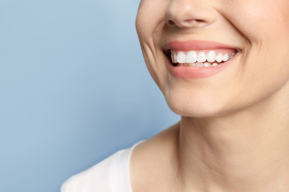 A Close Up Of A Woman 's Smile With White Teeth On A Blue Background — St Ives Dental Boutique In Saint Ives, NSW