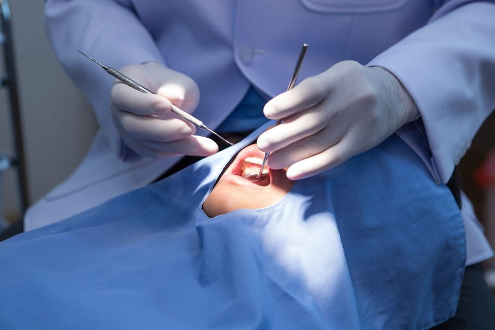 Dentist Examining a Patient's Open Mouth With Dental Tools Under Bright Light — St Ives Dental Boutique In Saint Ives, NSW