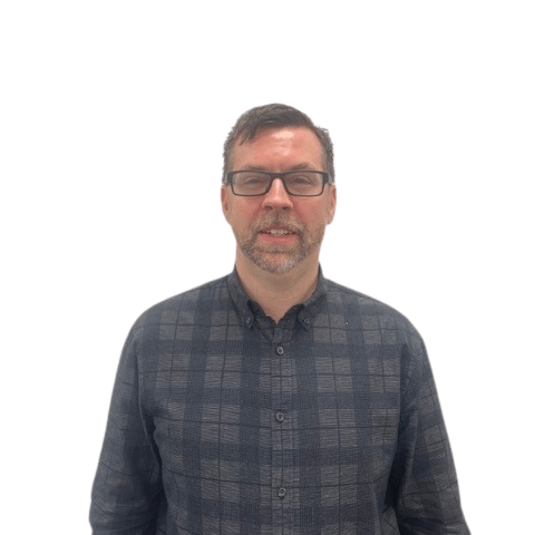 A man wearing glasses and a plaid shirt stands in front of a white background