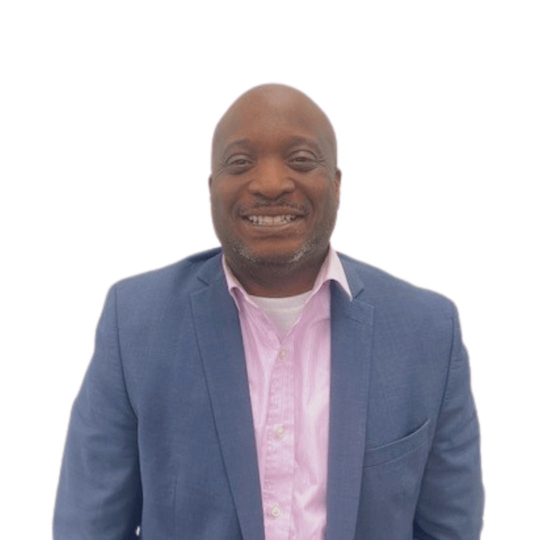 A man in a blue suit and pink shirt is smiling for the camera.