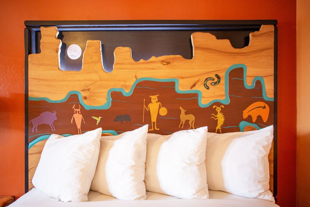 Hotel room at Southwest Inn Sedona featuring bed with rustic wooden headboard and white pillows