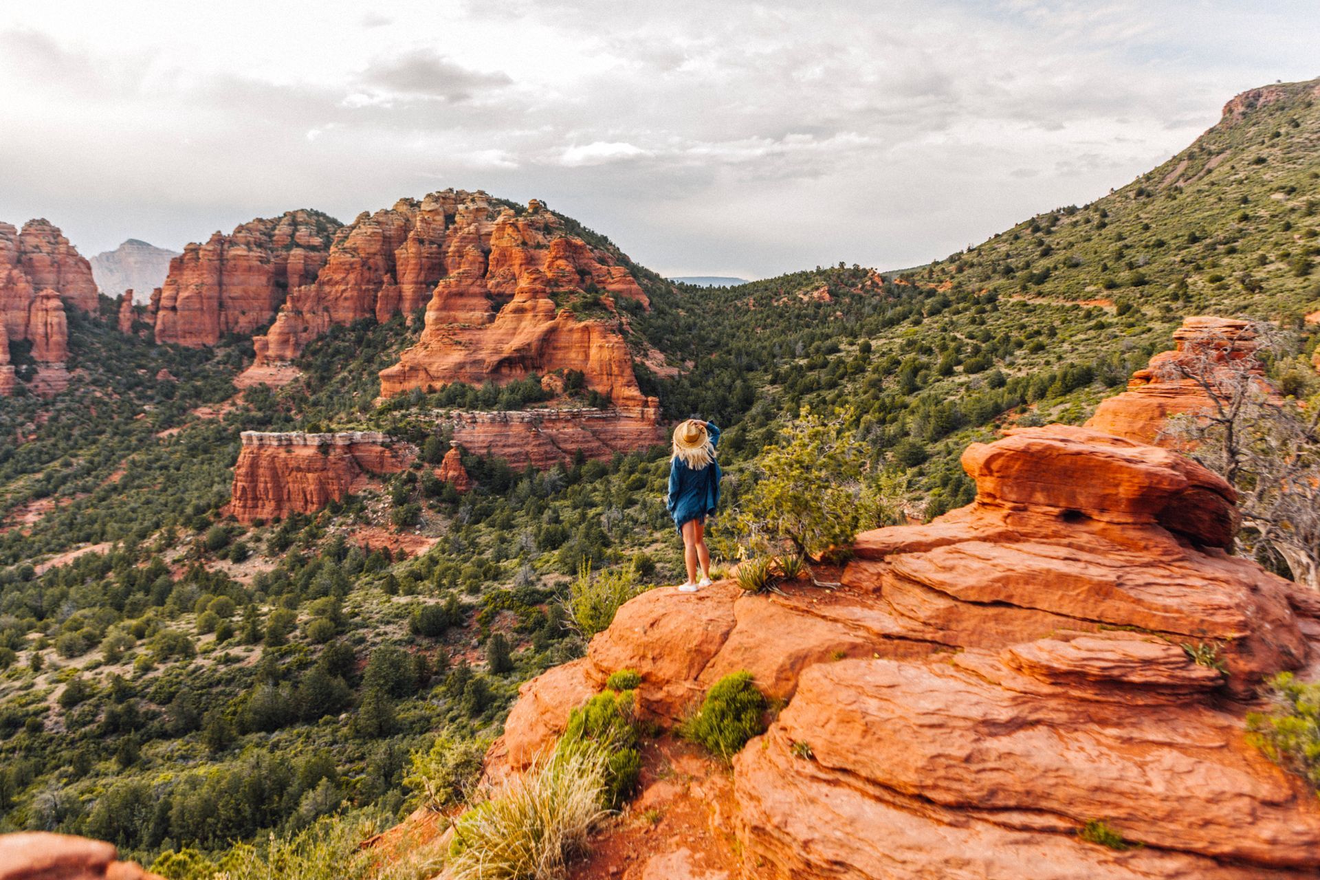 Woman standing on rocky cliff overlooking Sedona valley near Southwest Inn Sedona
