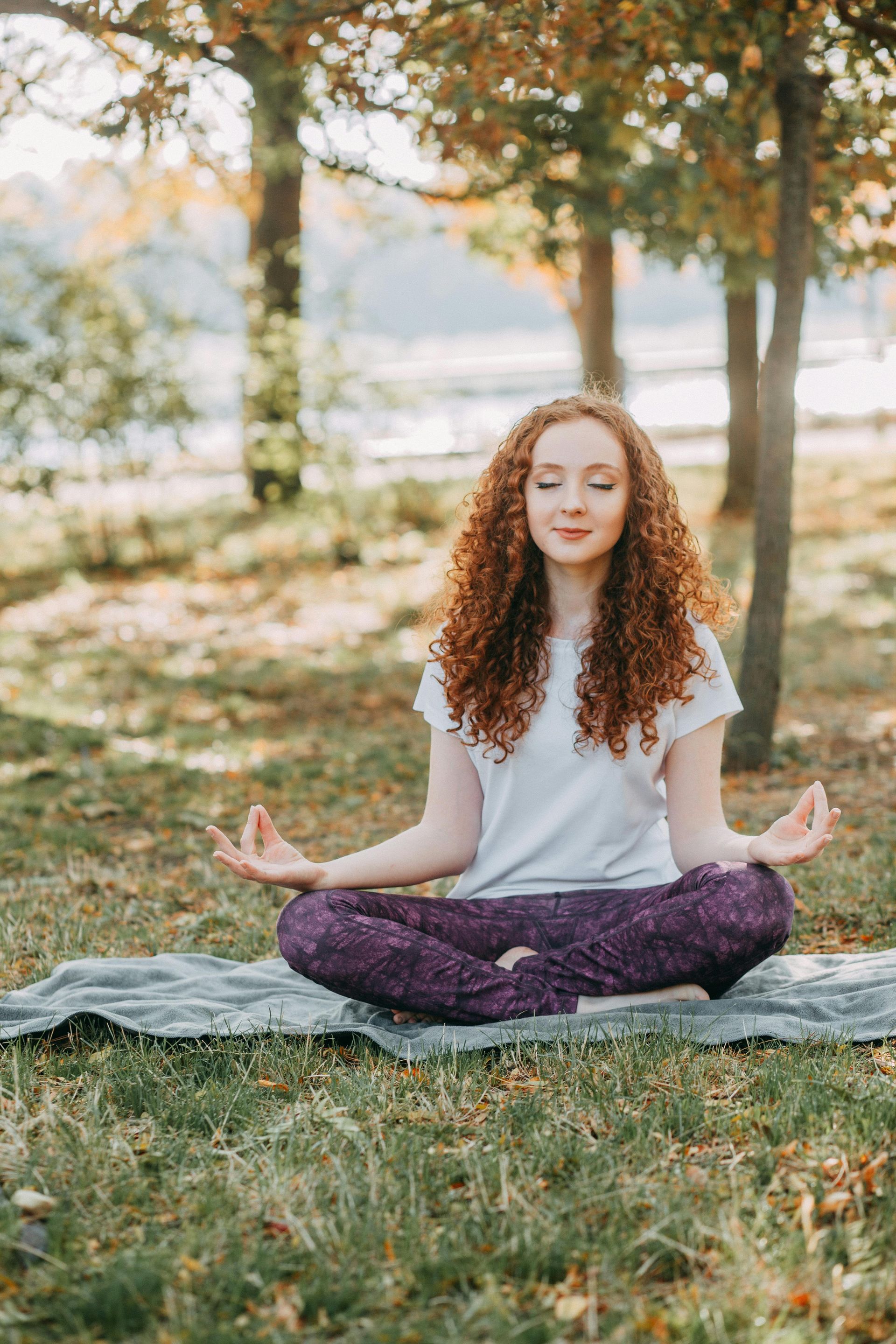 Woman practicing yoga in lotus position on a mat at a Sedona park near Southwest Inn Sedona