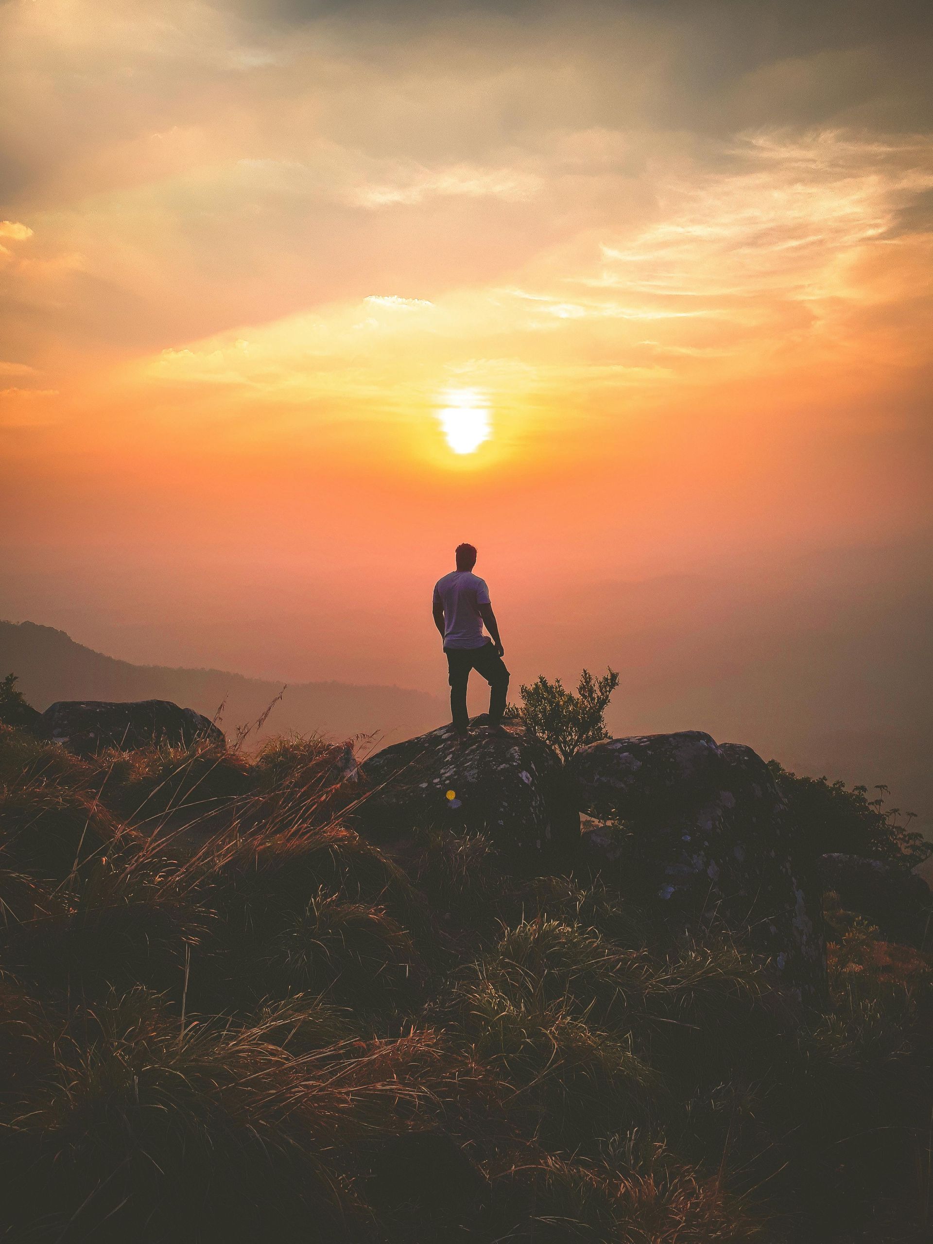 Man standing on hilltop watching Sedona sunset near Southwest Inn Sedona