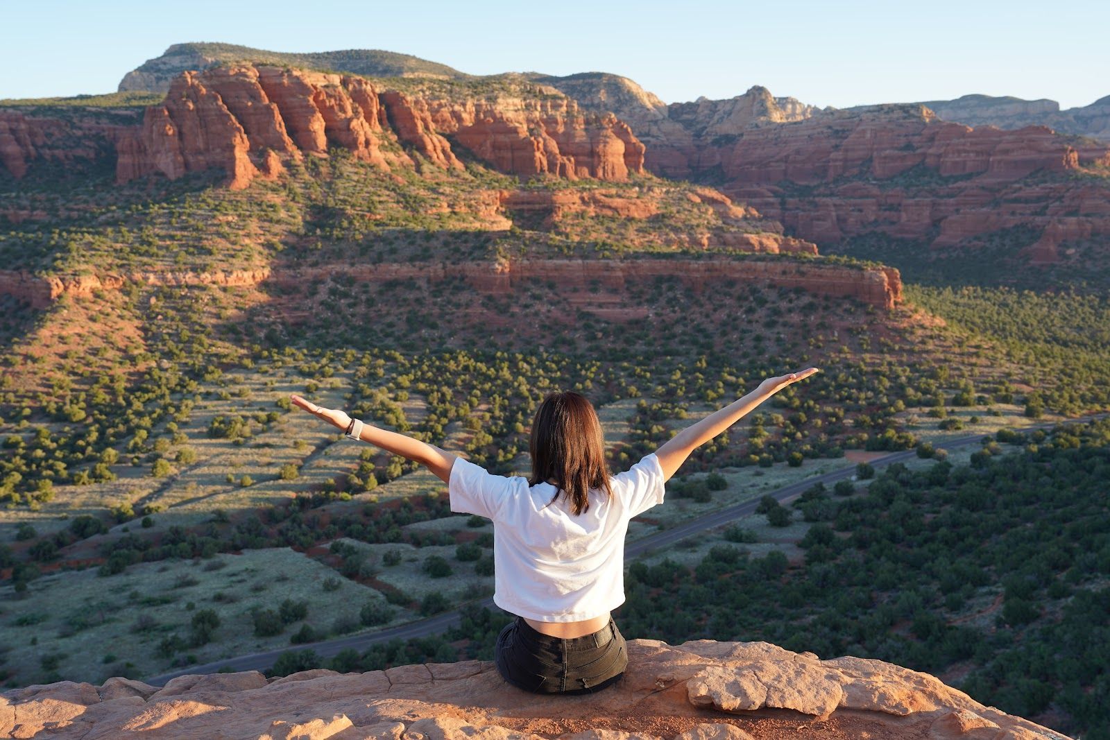 Traveler with arms raised at a Sedona red rock overlook