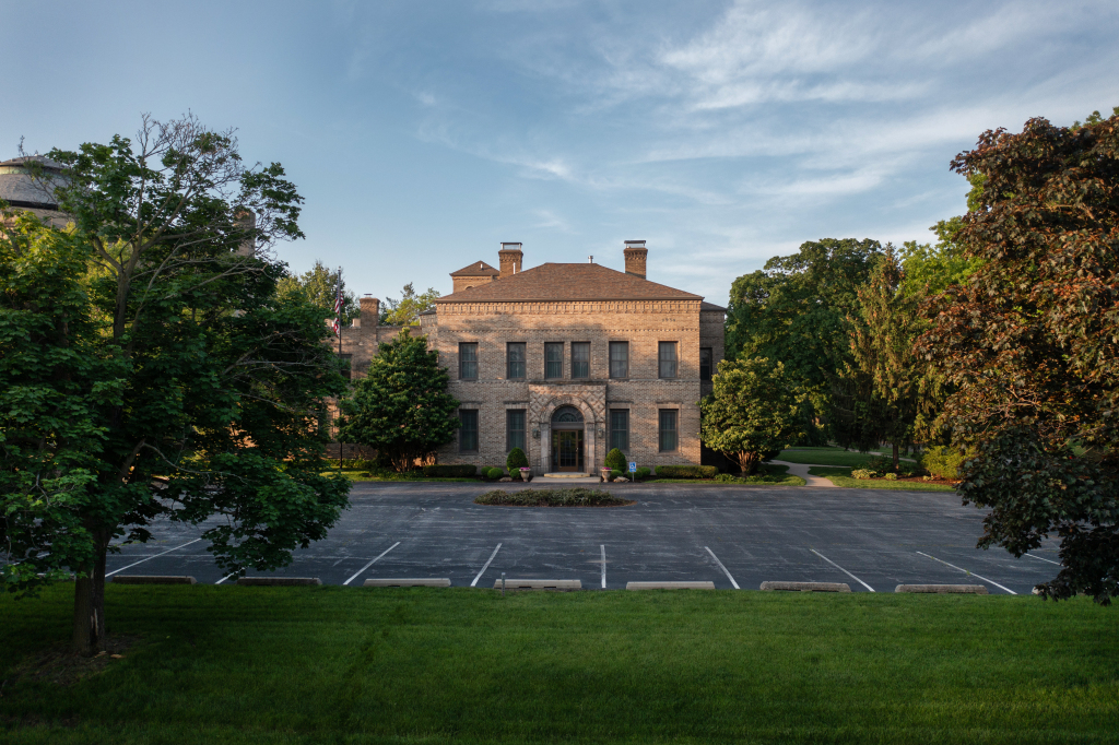 Stone building with parking lot and trees.