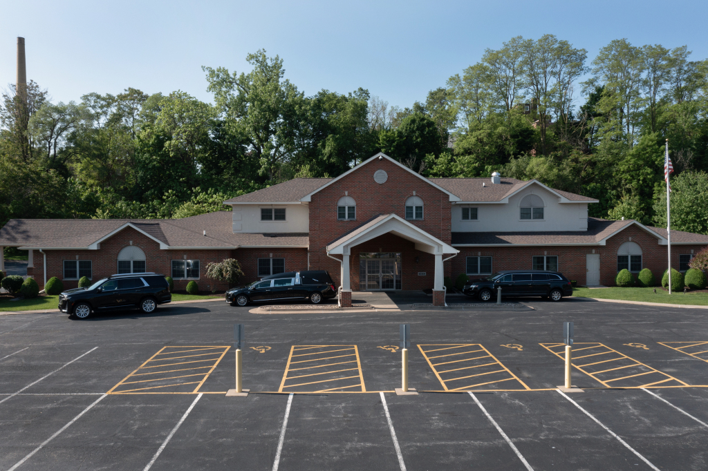 Brick building with cars parked in front, likely a business or office, with a large parking lot.