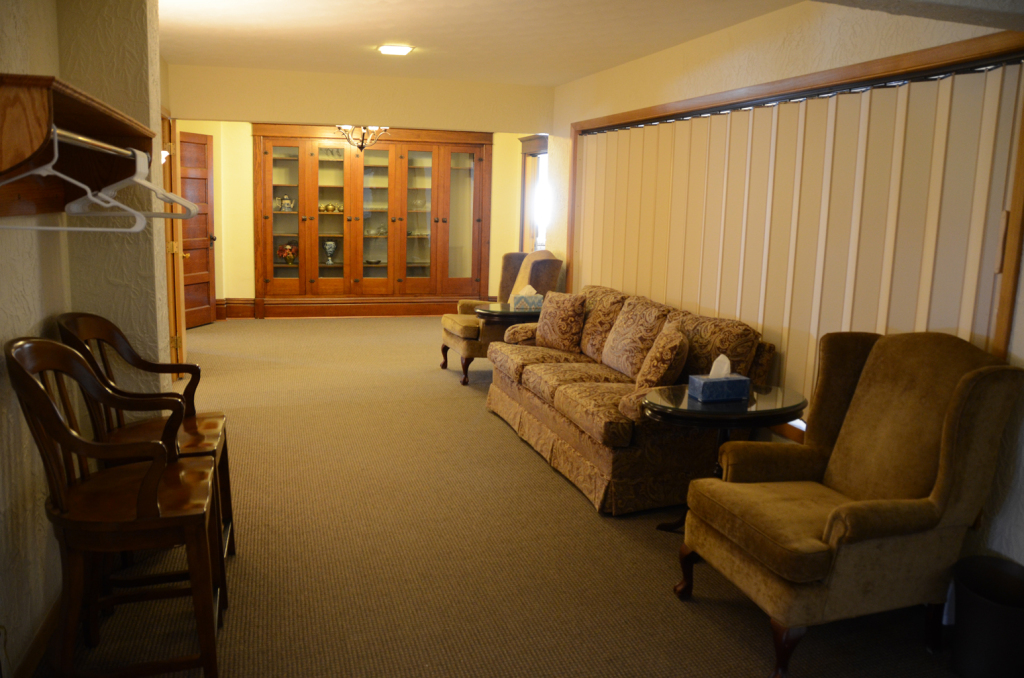 A room with chairs, a couch, and built-in cabinets, likely a waiting area with neutral colors.