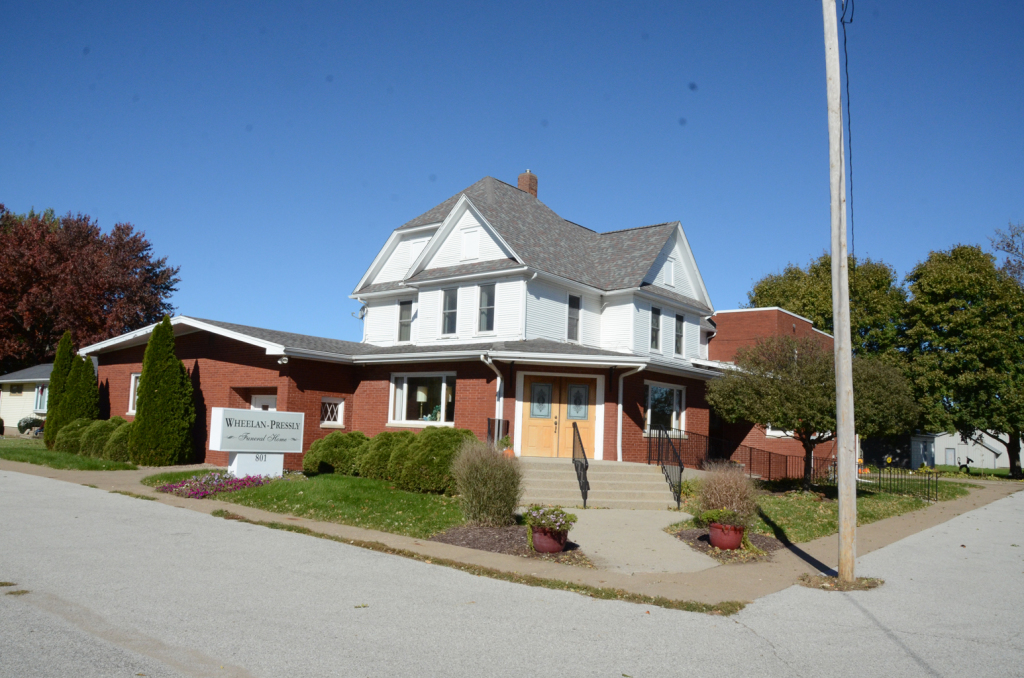 Church building with red brick exterior and white upper floors, blue sky.