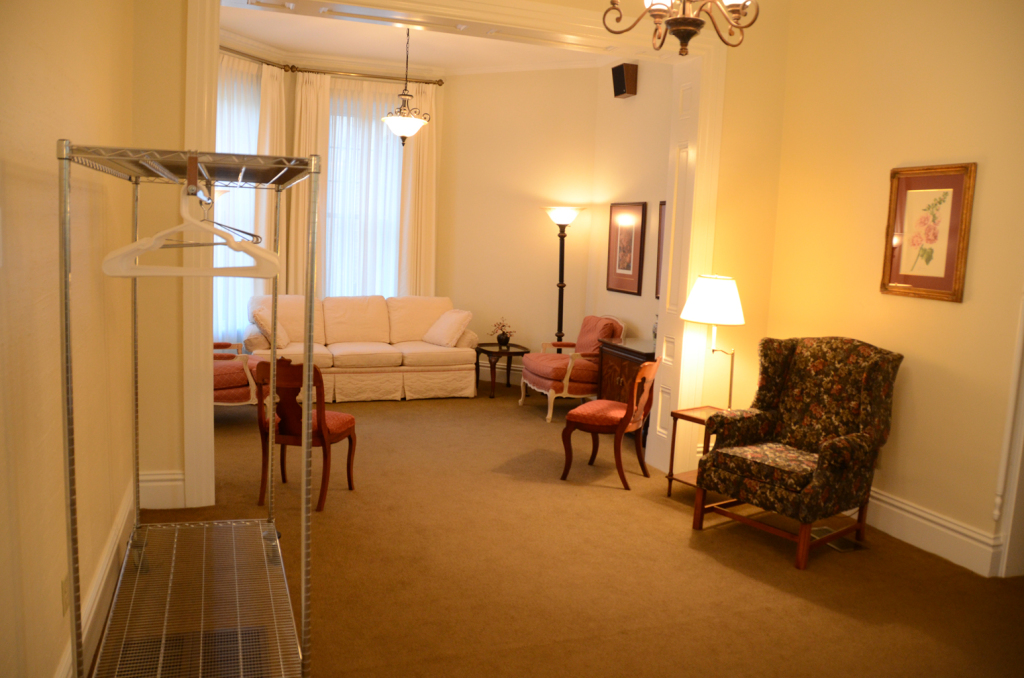 A waiting room with an open closet, seating, and decorative lighting.