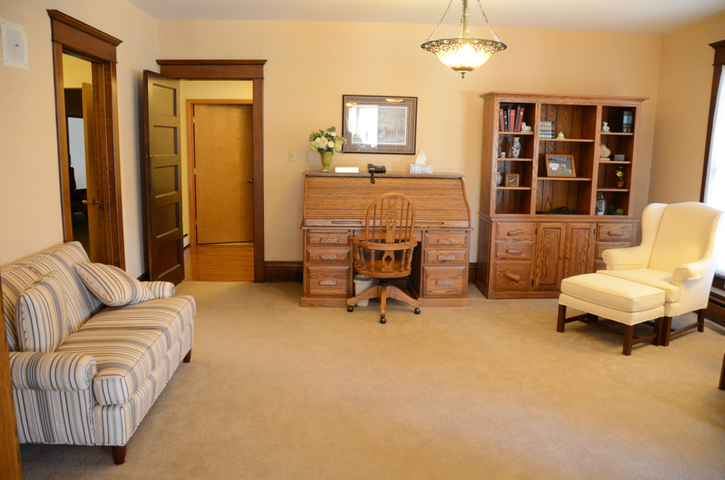Living room with sofa, desk, cabinet, armchair, and open doorway.