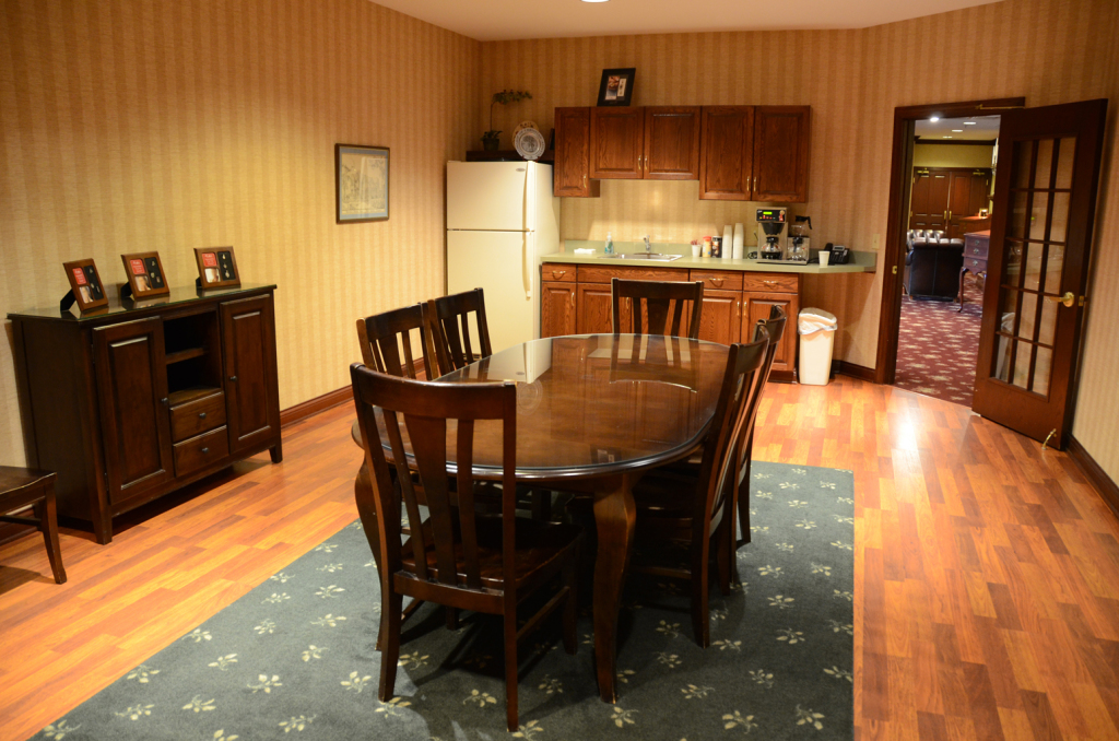 Dining room with table, chairs, cabinets, refrigerator, and doorway. Wooden floor and patterned rug.