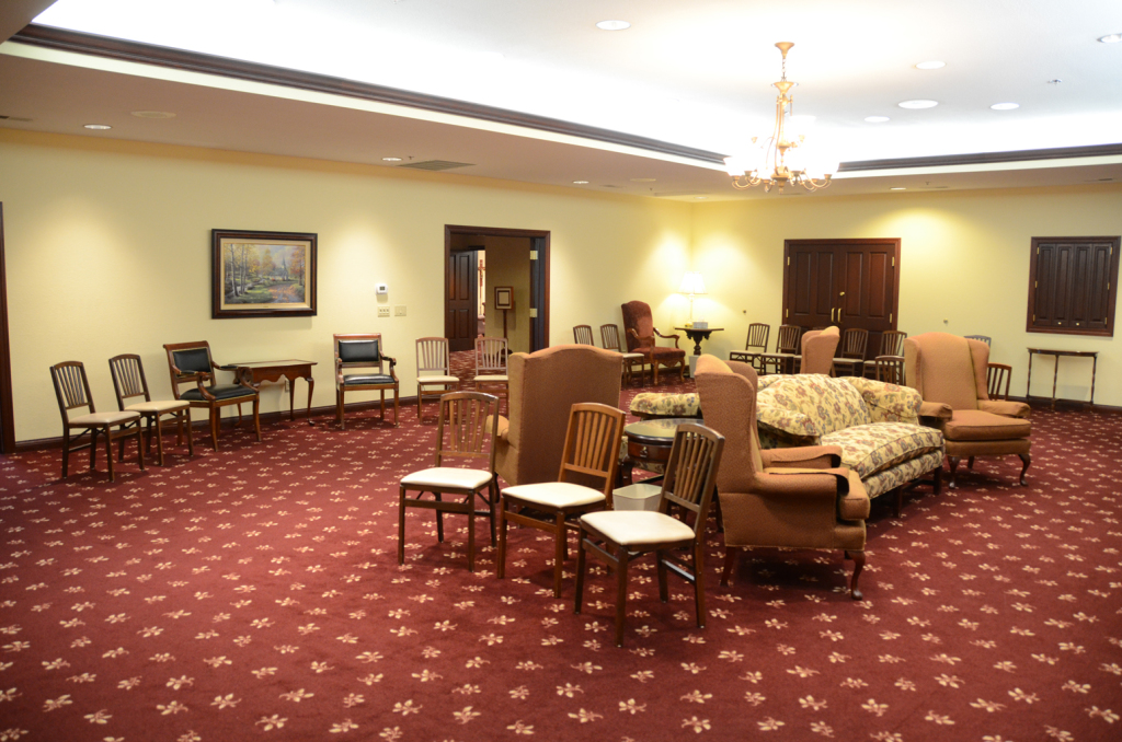 Formal room with red patterned carpet, various seating arrangements, and artwork on the wall.