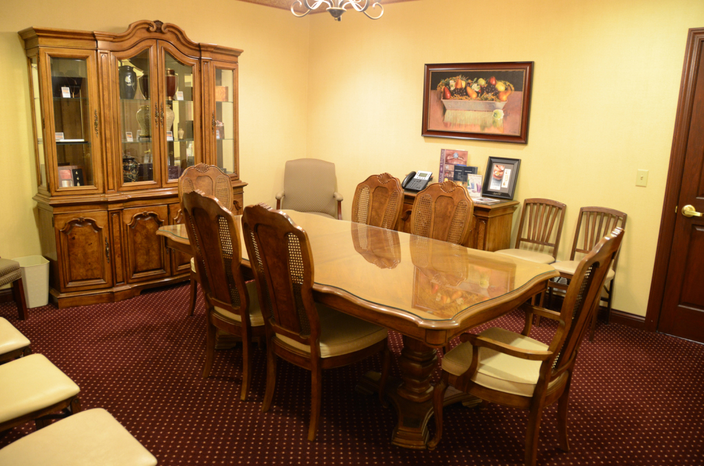 Formal dining room with large wood table, chairs, and ornate hutch. Carpeted floor, beige walls.