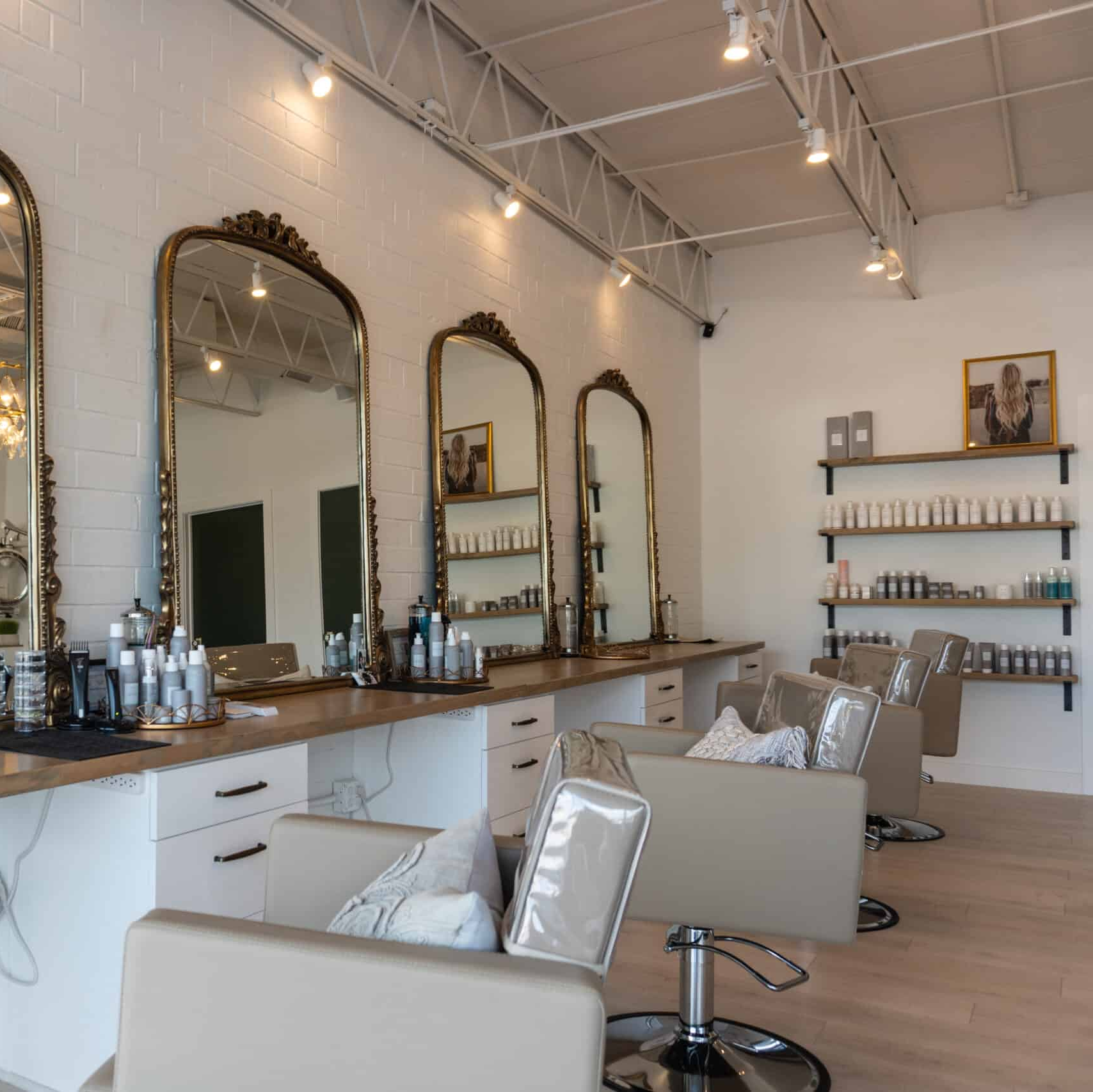 Hair salon interior with mirrors, styling stations, chairs, and product display shelves.