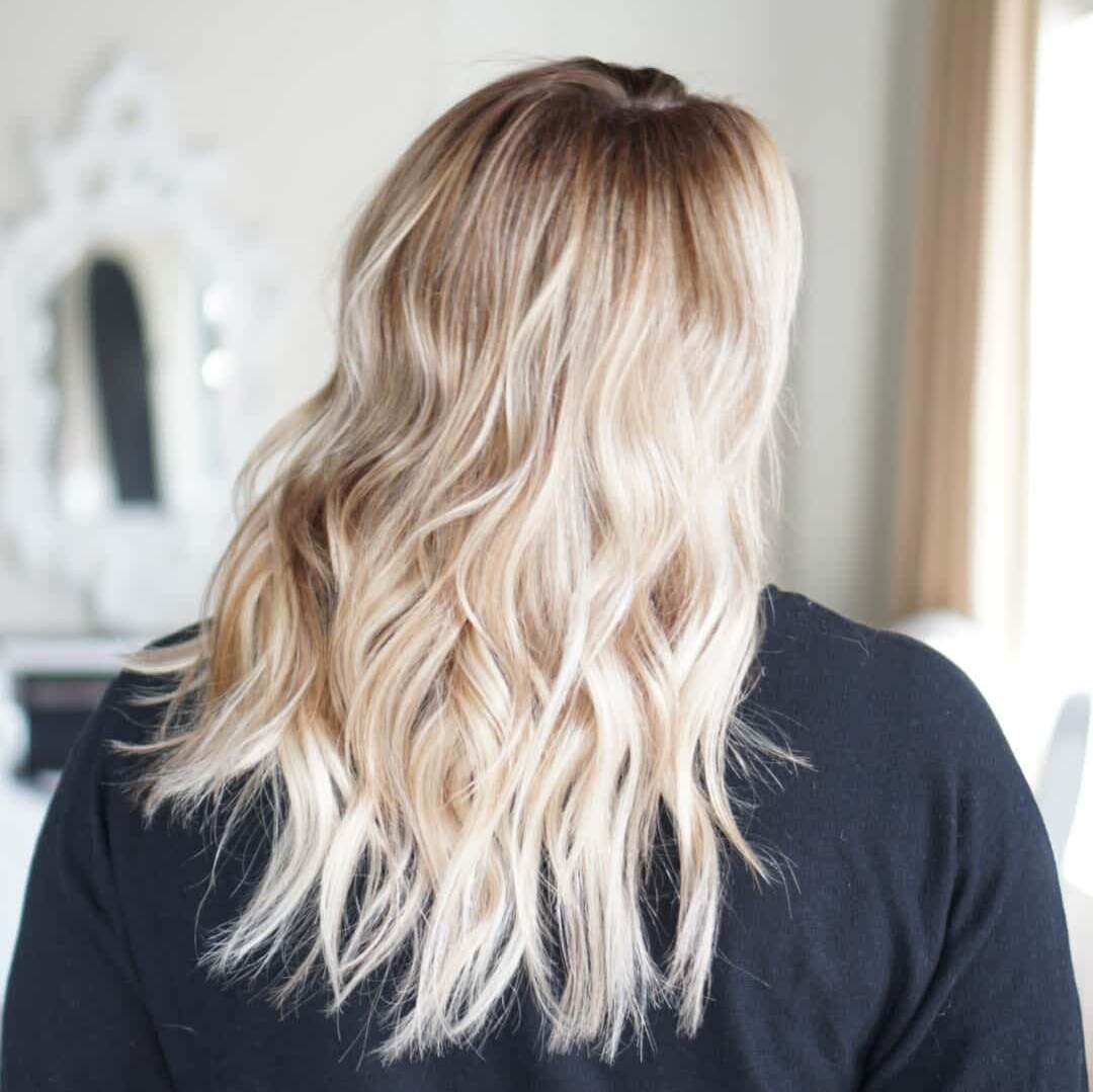 Woman with blonde ombre hair, wearing a black top.