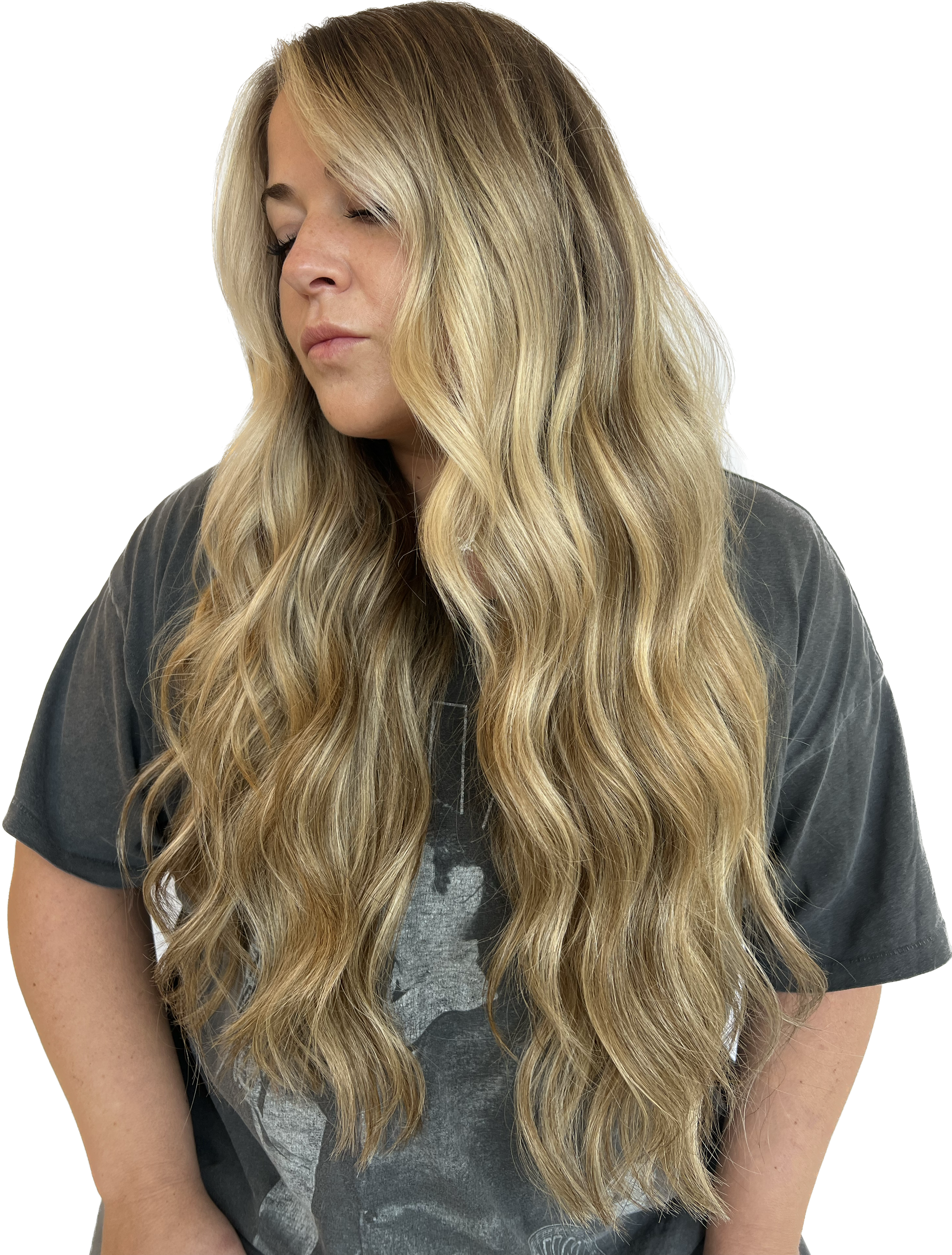 Woman with long, wavy blonde hair looks down, wearing a gray t-shirt.